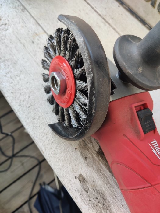 Renoveringsverktyg med slipborste monterat på röd vinkelslipmaskin, används för att ta bort gammal färg.