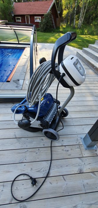 Poolrobot ligger på en träterrass med pool i bakgrunden, redo att förenkla underhållet.