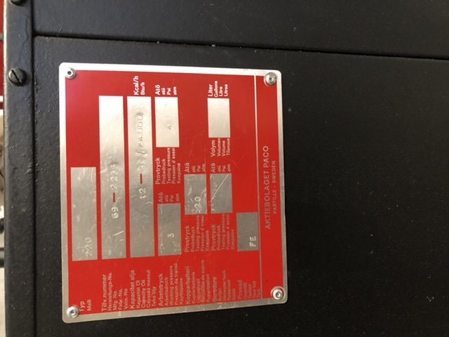 Röd informationsskylt på svart bakgrund för en värmepanna med tekniska specifikationer.