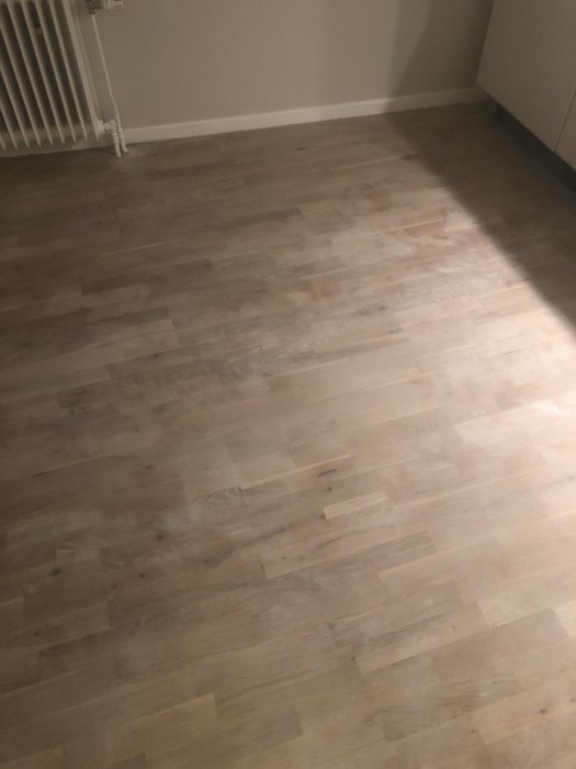 Slipat ekparkettgolv med fläckar efter vitoljebehandling som inte torkat jämnt.