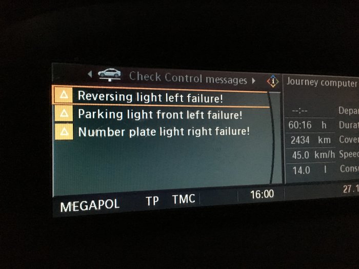 Fordonets display med varningsmeddelanden om trasiga lampor och ett infotainmentsystem.