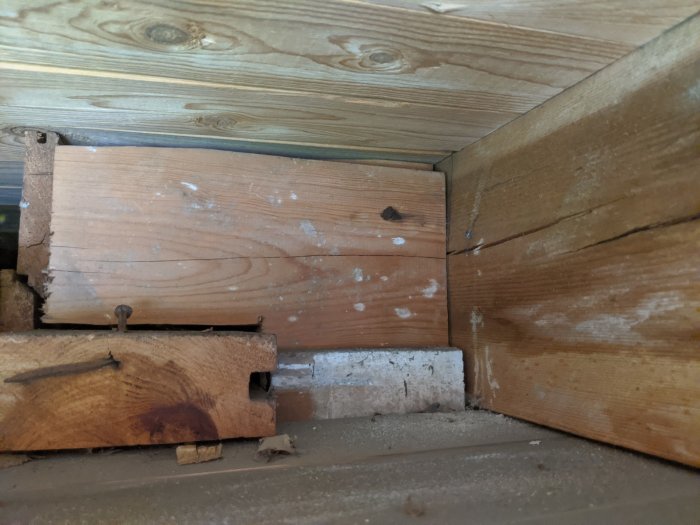 Nedslitet träbjälklag och råspont under balkong, skador synliga nära hängrännan.