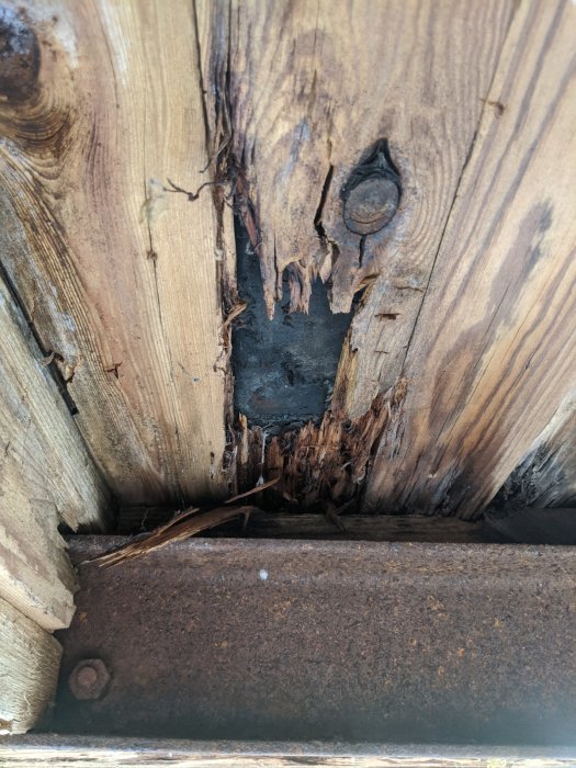 Vattenskadat träbjälklag med angripet råspont och rostig balk i en äldre balkongkonstruktion.