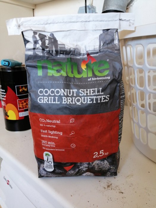 Påse med kokosskal grillbriketter på en köksbänk, CO2-neutral och snabbtändande 2,5 kg.