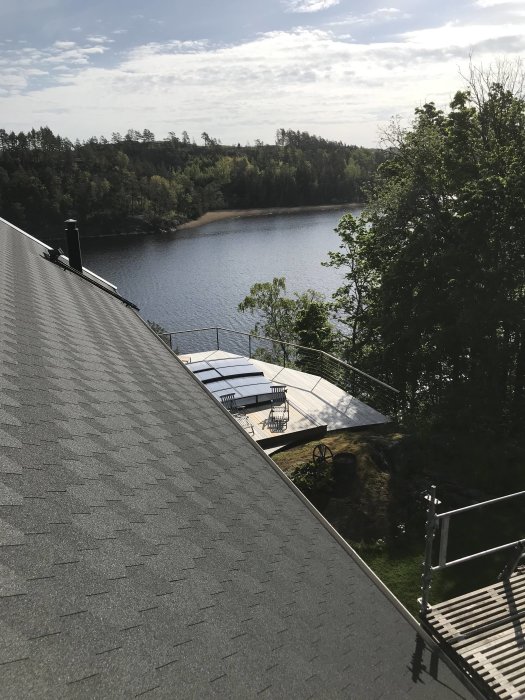 Termiska solfångare installerade på taket av ett hus med utsikt över en sjö och skog i bakgrunden.