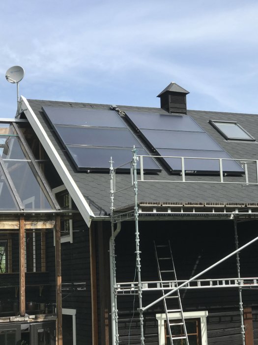 Solpaneler installerade på ett hus med väntande inkoppling, byggställning i förgrunden.