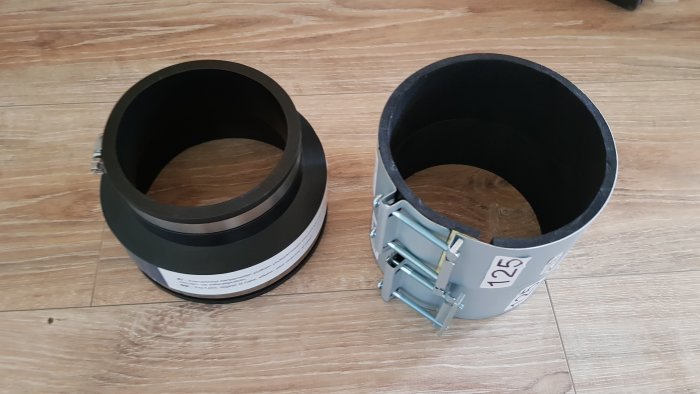 Två ventilationsrörskopplingar på ett trägolv, en med klämma och en utan.