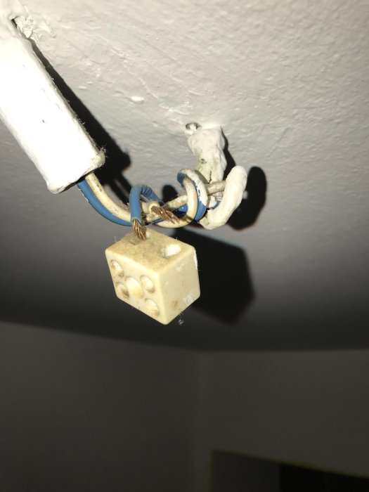 Elkablar och en gammal sockerbitsskarvning hänger från ett tak i behov av installation av lampa.