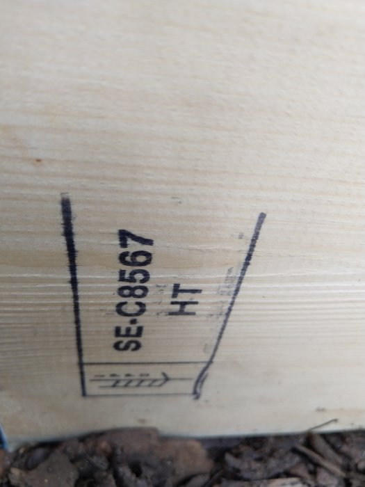 Närbild av en träpallkragens sida med ISPM 15-märkning "HT" vilket indikerar värmebehandling.