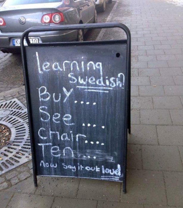 Svart trottoarpratare med text "learning Swedish" och orden "Buy See Chair Ten" skrivna för att låta som "Bye See You Later" på svenska.