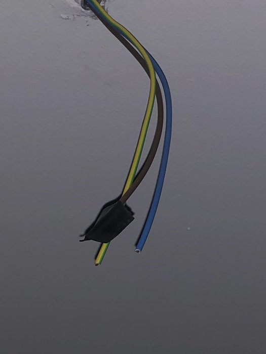 Elektriska kablar med gul/grön jordning, blå nolla och brun fas kommer ut från taket.