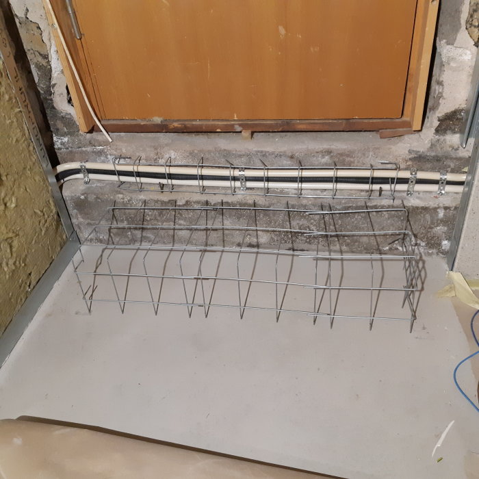 Armeringsnät formar ett trappsteg vid golvet, med kabelrör som ska gjutas in, anslutet till gammal bottenplatta.