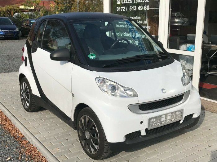 Vit Smart Fortwo parkerad framför en byggnad, används för rengöring av pensionär.