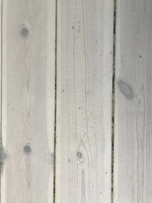 Nyslipat och vitmattlackat furugolv med synliga sprickor och gulnade skarvar.