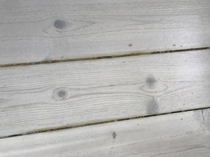 Nyslipat furugolv och trappa med sprickor och gulnade fogar efter renovering.