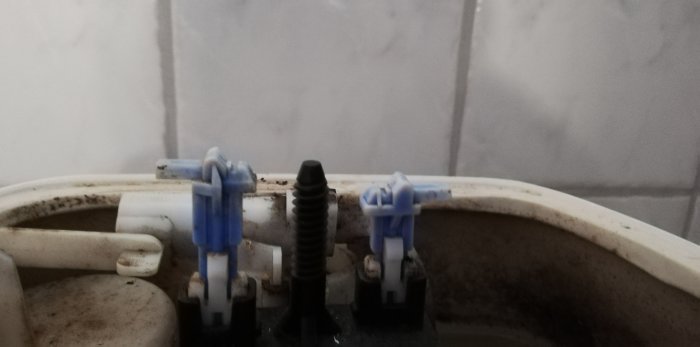 Inre mekanismen för en Ifö Cera toalett där den blåa spolningsarmen är lägre än den andra.