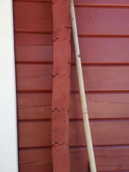 Rödmålat trähus med en lutande tegelstapel vid sidan illustrerar markens sättning över tid.