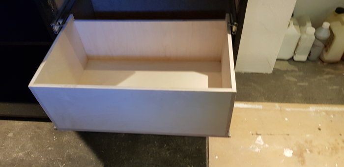 Öppen verkstadslåda av björkplywood och mdf på ett verkstadsgolv, redo för ytbehandling.