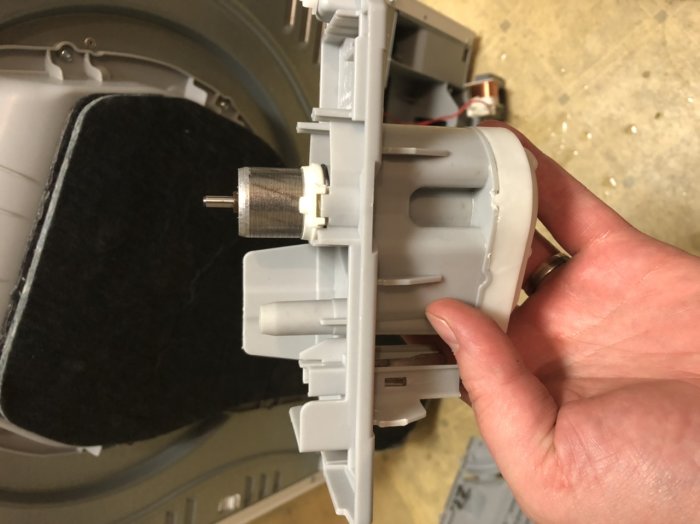 En hand håller en demonterad pump med sitt rotorskaft synligt, redo för underhåll eller reparation.