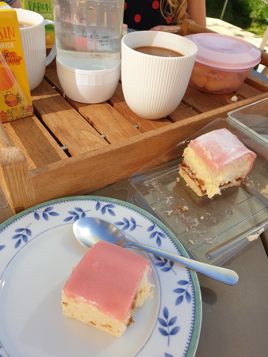 Fikabord på altan med kaffe, saft och en bit prinsesstårta på en tallerrik.