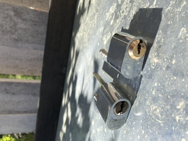 Två nya låskolvar monterade vid varandra på ett garageports metallblad som visar frågeställarens problem med låsbytet.