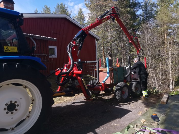 Svärfar använder traktors timmergrip och hydraulwinch för att lyfta gammal vedpanna.