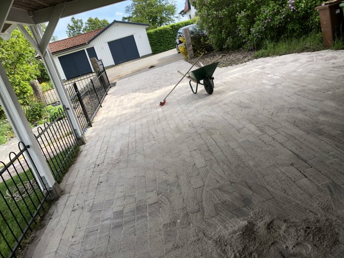 Renoverad uppfart med nylagt fogsand mellan stenplattorna, skottkärra och högtryckstvätt syns i bakgrunden.
