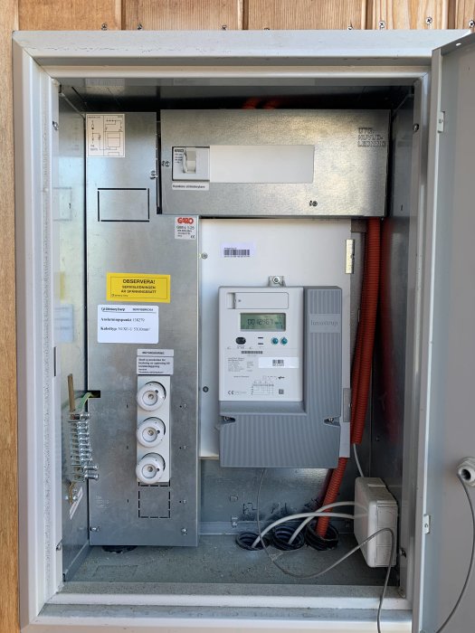 Elutrustningsskåp med säkerhetsbrytare, energimätare och ledningar, intyg för solcellsinstallation.