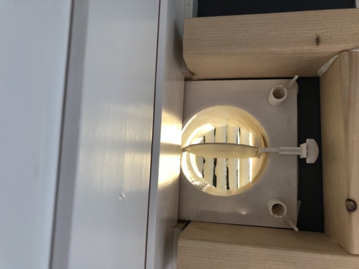 Hemmagjord träram för frånluftsadaptrar monterad över en tilluftsventil på vägg.