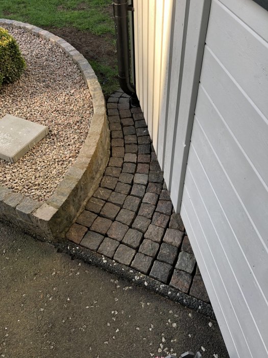 Nyligen sopad gångväg med kullersten och angränsande rabatt med stenmjöl.