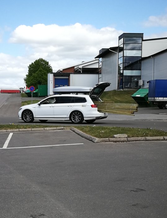 Bil med bakluckan öppen och osäkrade byggmaterial vid byggvaruhus utan synlig lastsäkring.