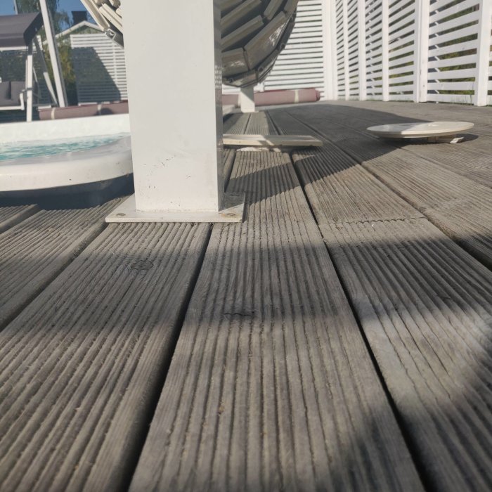 Trätrall som leder mot en pool med en del av en vit pelare och poolkant i synfältet.