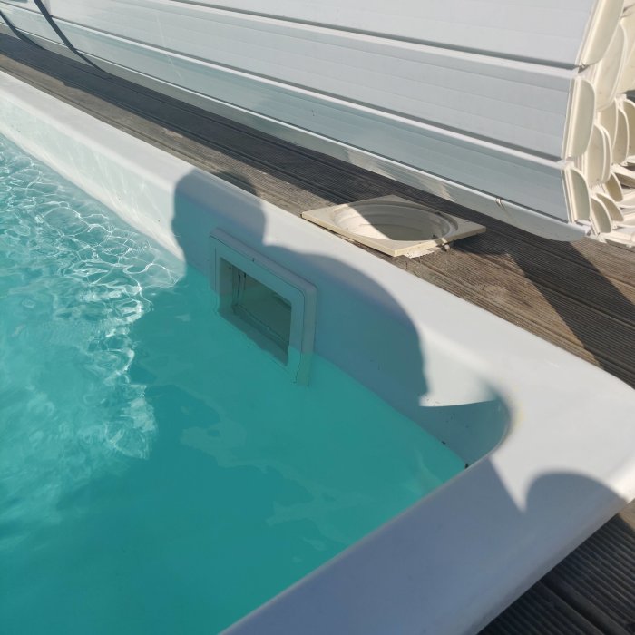 Poolkant och avlopp nära vattenytan, potentiell läckplats, soleksponering.
