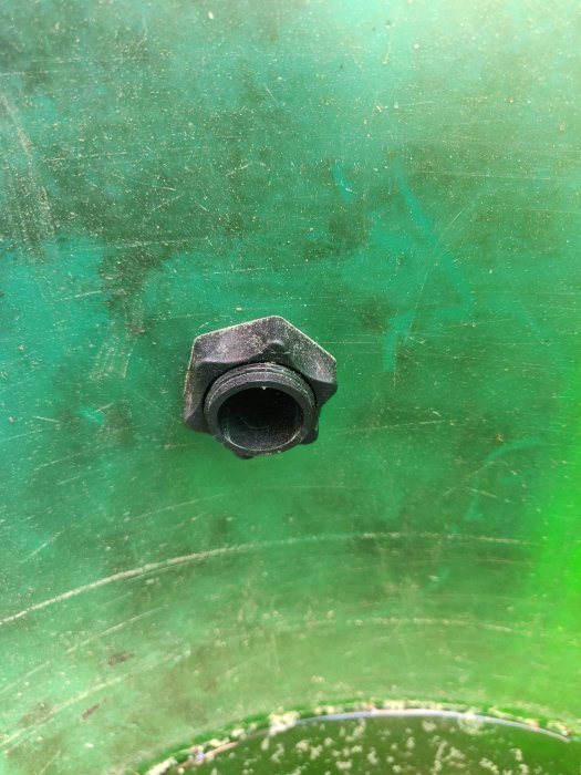 En tjockväggig grön tunna med en framträdande svart mutter på utsidan.