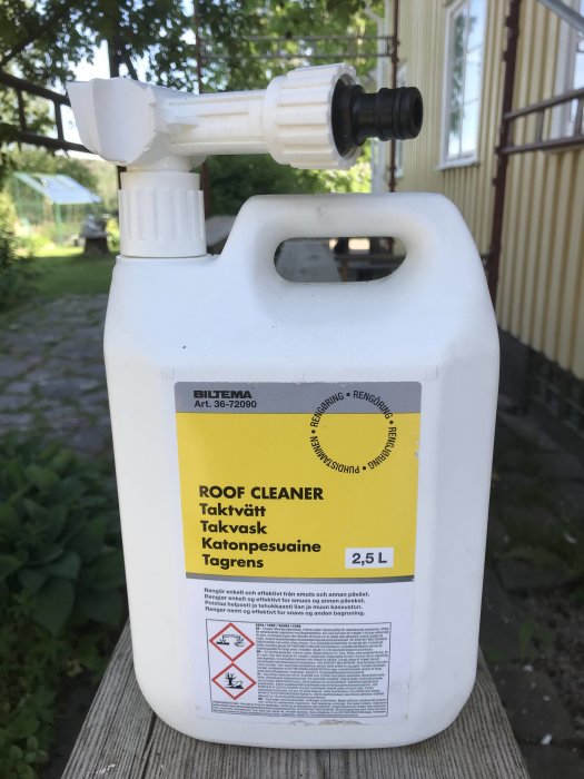 Plastflaska märkt "ROOF CLEANER" med sprutmunstycke, stående utomhus.