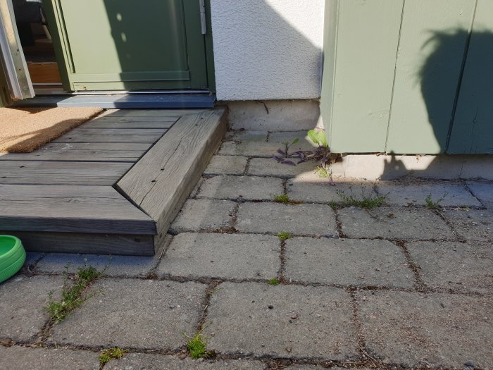 Altanens trall nära huset, som övergår till befintliga stenplattor, med dörröppningens nederkant synlig.