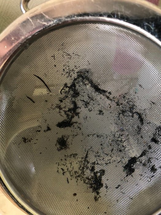 Partiklar som liknar hårdplast på ett metall durkslag, misstänkt från brunnsförfilter.