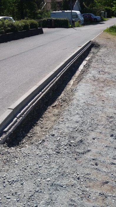 Nybyggd liten stödmur av betongblock längs med en grusslänt bredvid en väg.