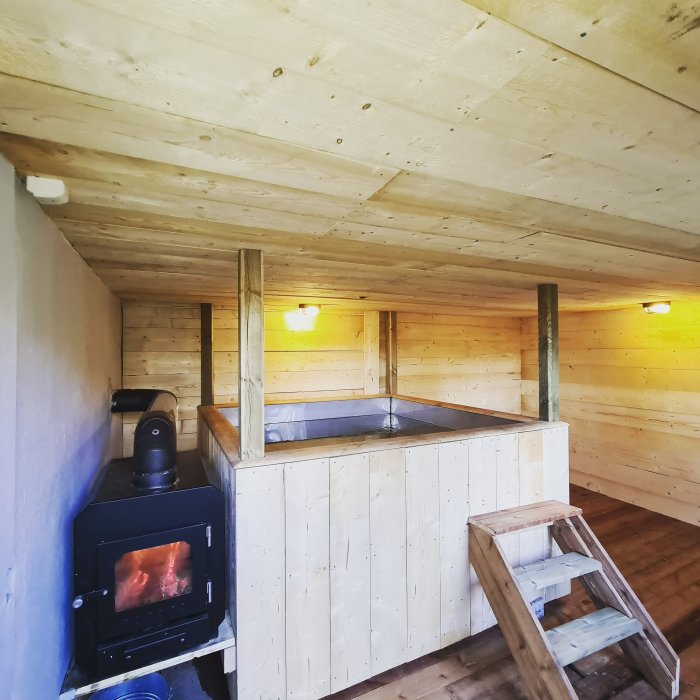 Inredd del av ett gammalt fårrhus ombyggt till badhus med vedeldad kamin och inbyggd badtunna av syrafast stål.