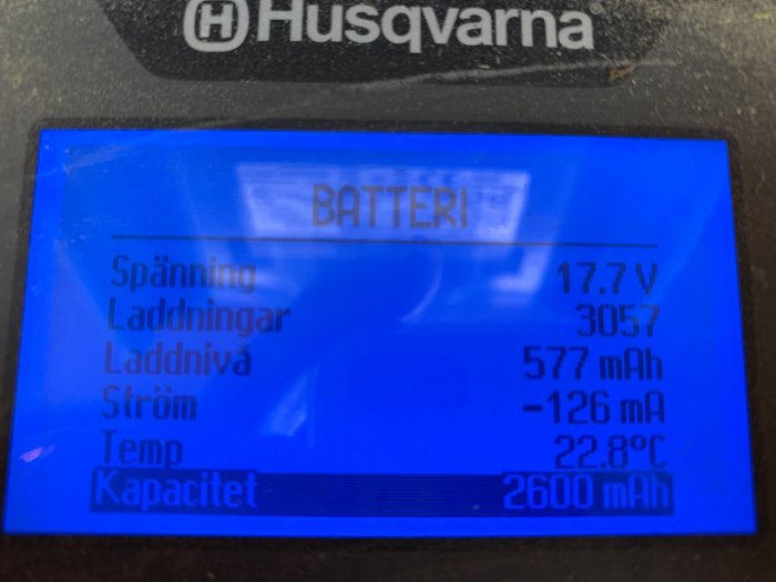 Display på en Husqvarna robotgräsklippare visar batteristatus med spänning och laddningsdata.