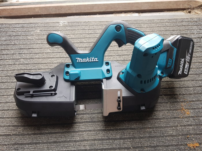 Makita elektrisk bandspackel på ett trägolv.
