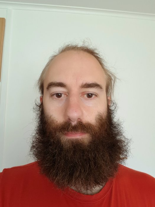 Man med röd tröja och stort skägg före trimning.