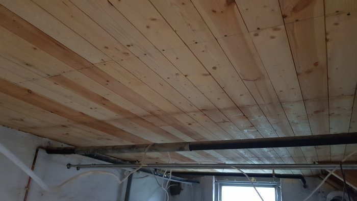 Ett nytt träinnertak efter borttagning av eternitskivor med synlig balk och rörinstallationer.
