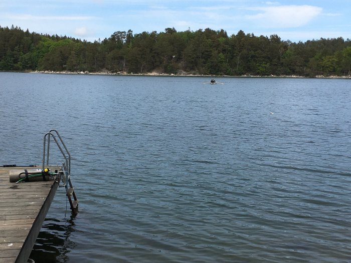 Brygga med dykutrustning vid sjö, 120l boj i bakgrunden, skogsmark i horisonten.