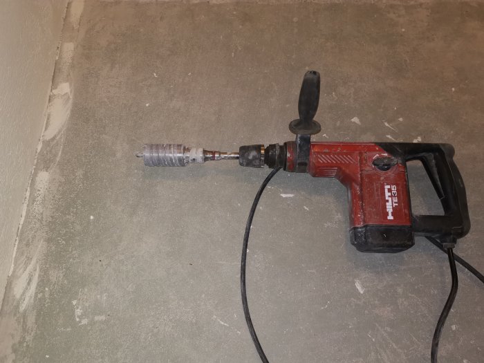 Borrmaskin av märket Hilti på ett dammigt betonggolv.