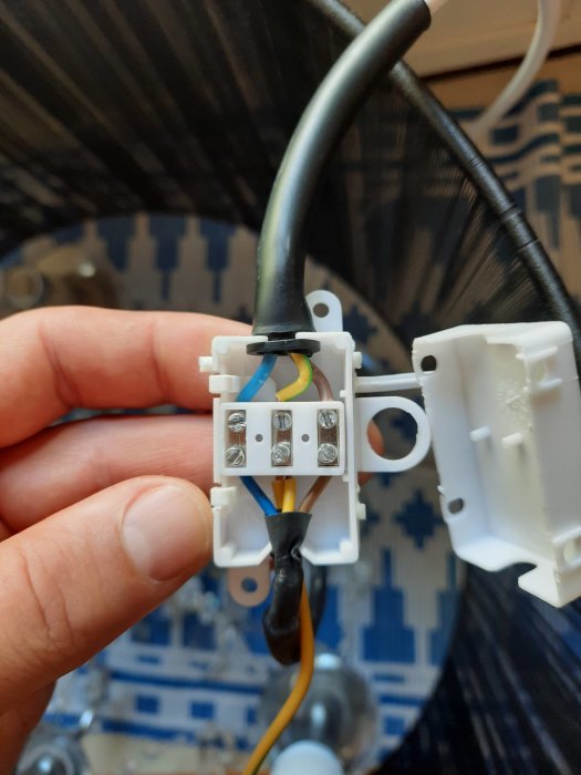 Inuti en kopplingsdosa med en grupp svarta, blåa och gula/gröna kablar före montering av taklampa.