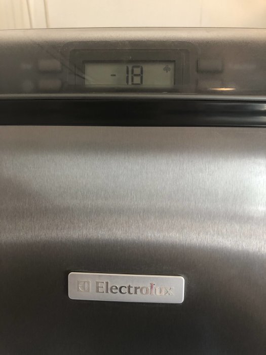 Frysens digitala display visar -18 grader Celsius, Electrolux-logotyp på silverfärgad yta.