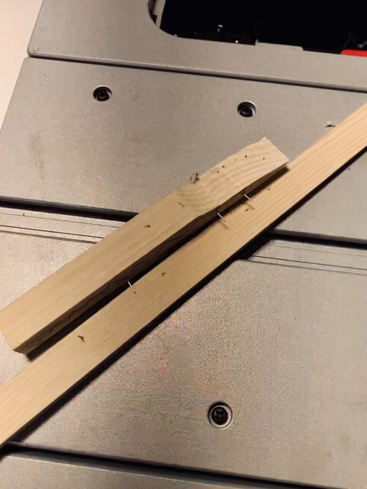 Två träbitar fästa ihop med 23 gauge-stift, minimala hål synliga.