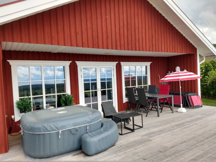 Altantak fäst vid husgavel ovanför en rymlig trädäck-altan med utemöbler och en uppblåsbar pool.