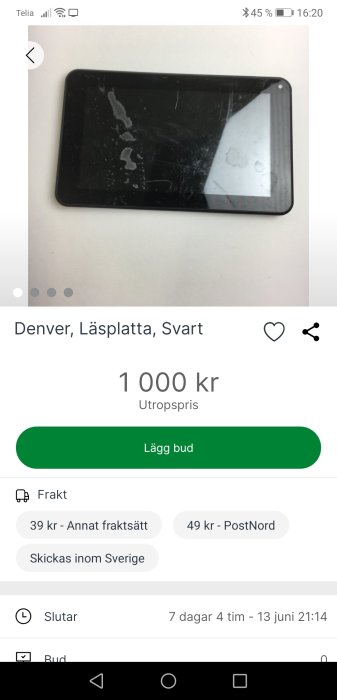 Svart läsplatta med märken och fläckar på skärmen, ligger på ett vitt underlag.